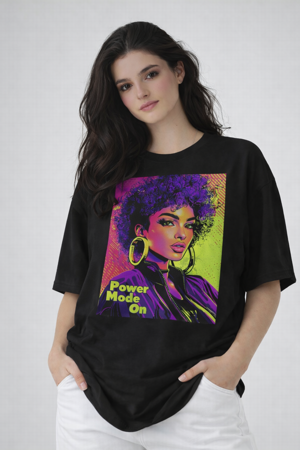Female model wearing black oversized t-shirt featuring colorful pop-art woman illustration, urban fashion look by Noiré.