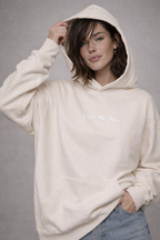 female model relaxed pose wearing oversized beige graphic streetwear hoodie minimal chest graphic streetwear outfit