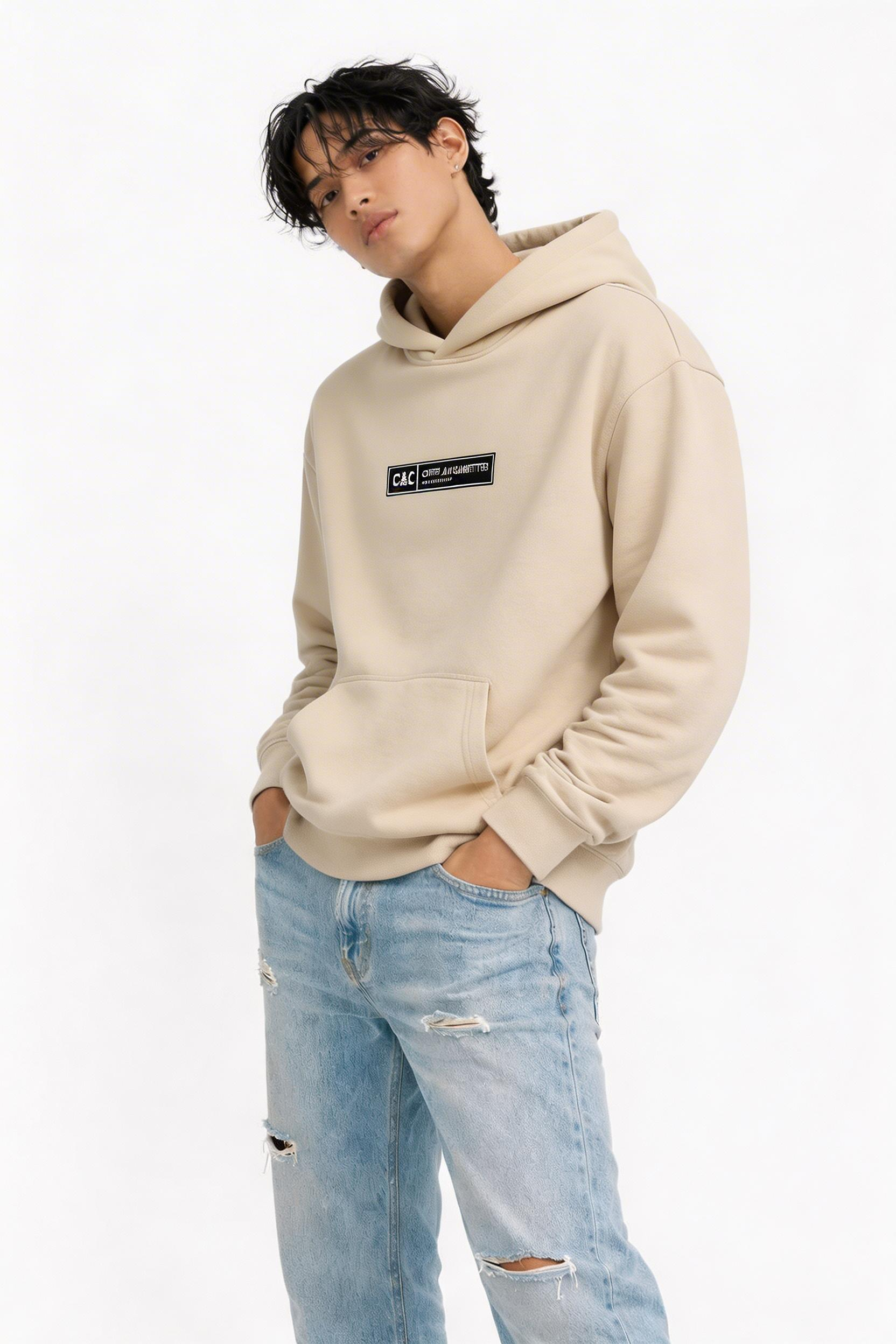 male model side pose wearing oversized beige graphic streetwear hoodie minimal chest logo streetwear fashion