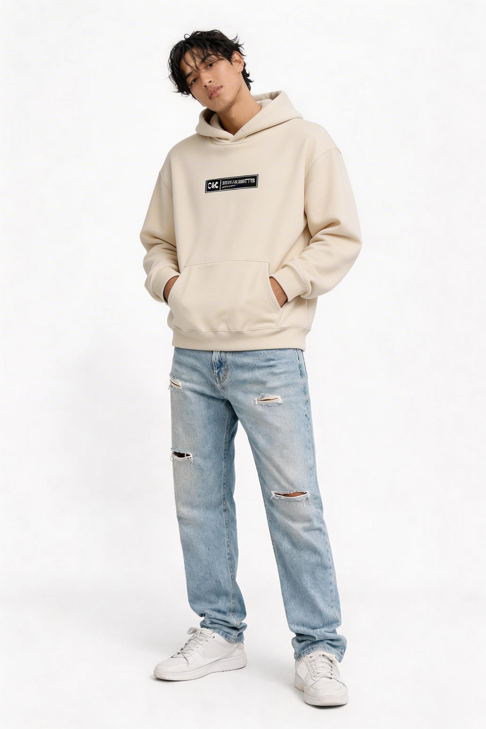 male model casual front pose wearing oversized beige graphic streetwear hoodie minimal chest logo urban streetwear outfit