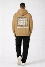 male model walking back pose wearing oversized brown streetwear hoodie living life graphic print urban streetwear clothing