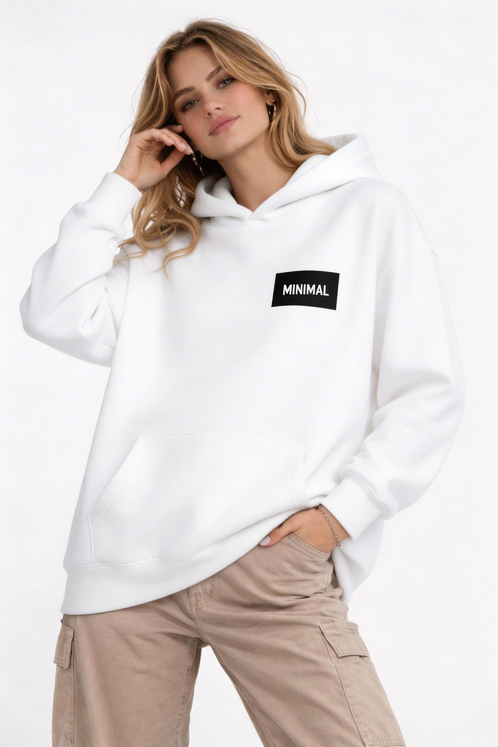 female model relaxed pose wearing oversized white minimalist hoodie small chest logo clean streetwear fashion