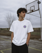 male model standing courtside wearing oversized white graphic t shirt 90s era chest logo urban streetwear outfit
