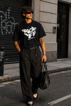 model walking front view wearing relaxed fit black graphic t shirt back off statement design urban streetwear outfit