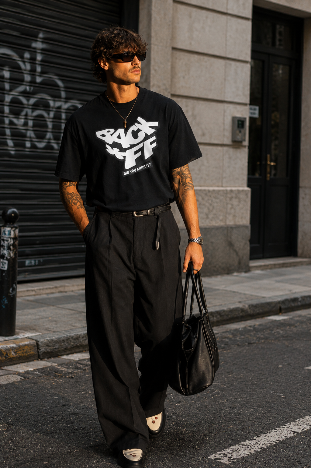 model walking front view wearing relaxed fit black graphic t shirt back off statement design urban streetwear outfit