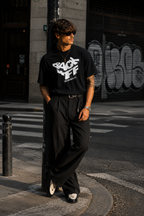 model leaning street pose wearing oversized black graphic t shirt back off typography design streetwear fashion