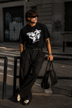 model leaning rail pose wearing oversized black graphic t shirt back off design graphic streetwear