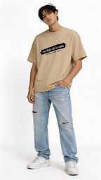 male model wearing oversized beige graphic streetwear t-shirt me bajo de la vida typography design urban fashion close up