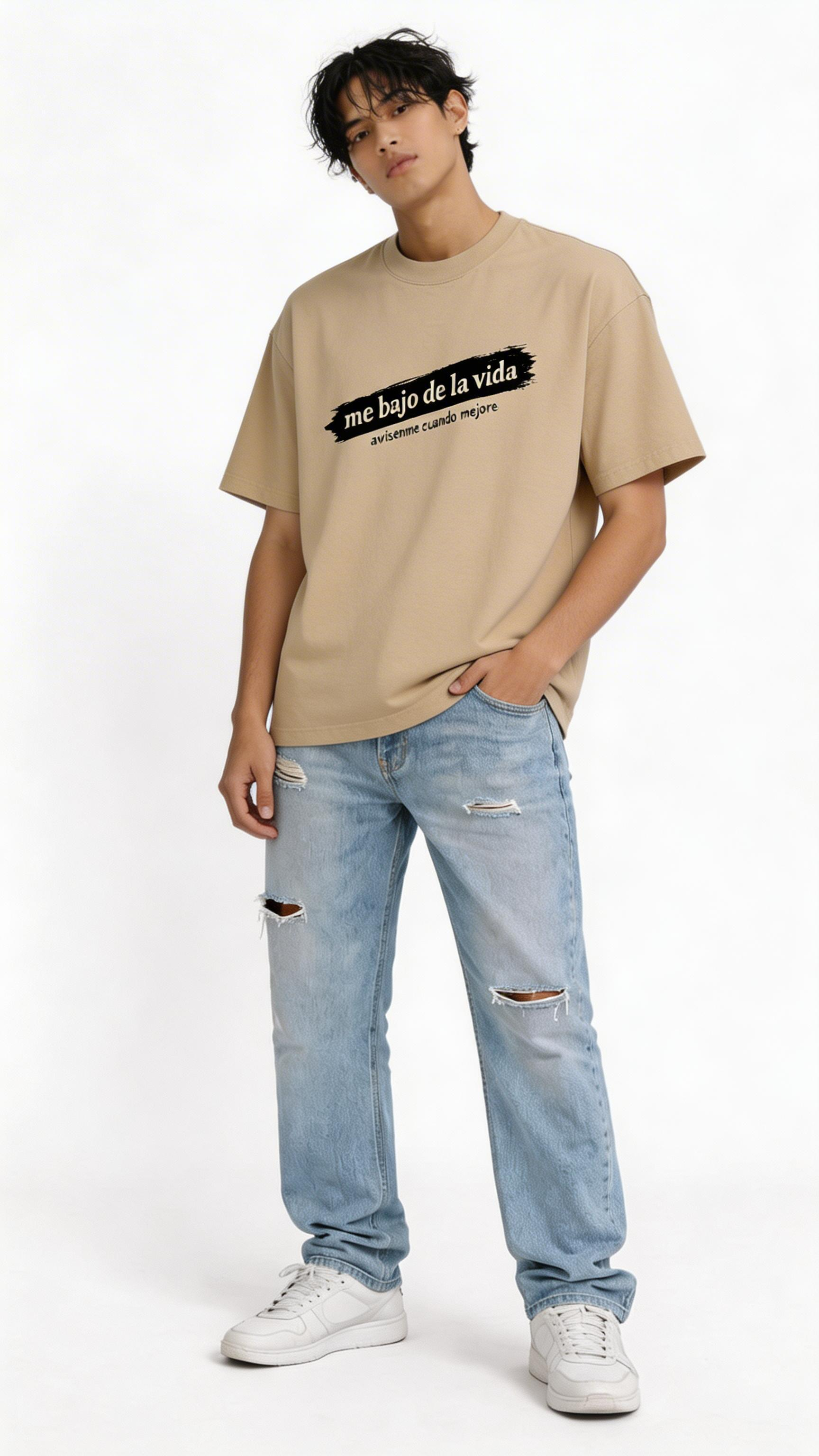 male model wearing oversized beige graphic streetwear t-shirt me bajo de la vida typography design urban fashion close up