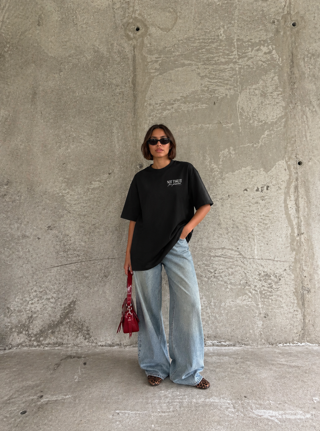 model walking wearing oversized black graphic t-shirt urban streetwear outfit