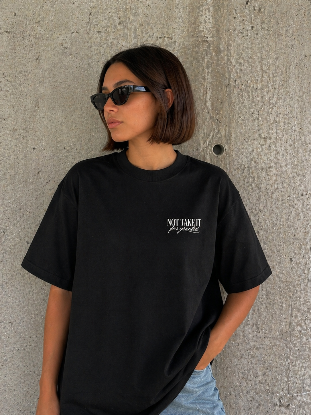model wearing oversized black graphic t-shirt front minimalist logo urban streetwear outfit