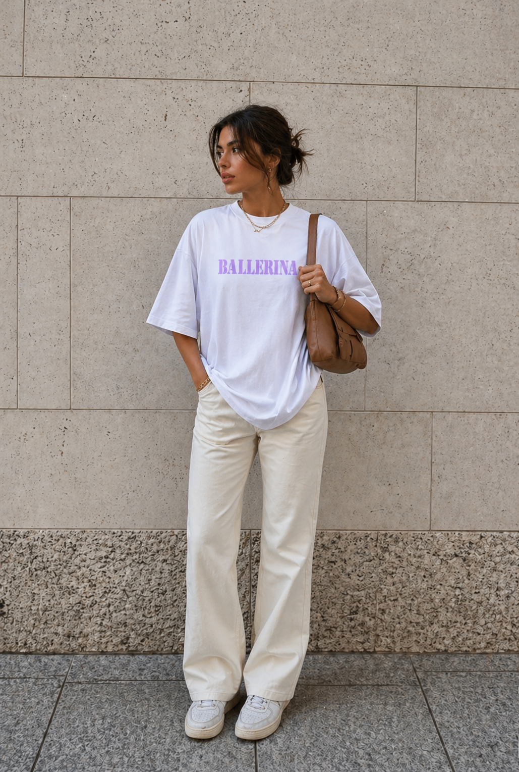 model standing against stone wall wearing oversized white ballerina graphic t-shirt cream wide leg pants urban streetwear outfit