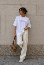 model standing against stone wall wearing oversized white ballerina graphic t-shirt cream wide leg pants urban streetwear outfit