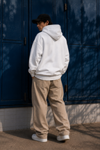 male model back view wearing blank oversized white hoodie relaxed fit minimalist streetwear outfit