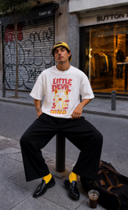 male model facing camera wearing oversized white graphic t shirt with little devil statement graphic streetwear fashion