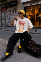 male model drinking iced coffee wearing oversized white graphic t shirt featuring colorful little devil artwork graphic streetwear