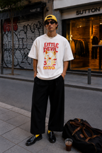 male model standing front view wearing oversized white graphic t shirt with little devil cartoon design urban streetwear outfit