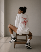 model seated on chair back pose wearing oversized white ballerina sweatshirt red back graphic streetwear fashion