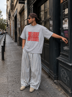 male model standing on urban street wearing oversized sport gray graphic t shirt with red influence typography design and relaxed streetwear fit urban streetwear outfit