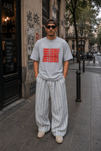 male model facing camera wearing oversized heather gray graphic t shirt with stacked influence typography print and relaxed fit streetwear fashion