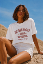 model seated portrait wearing white oversized graphic t shirt monaco riviera typography graphic streetwear