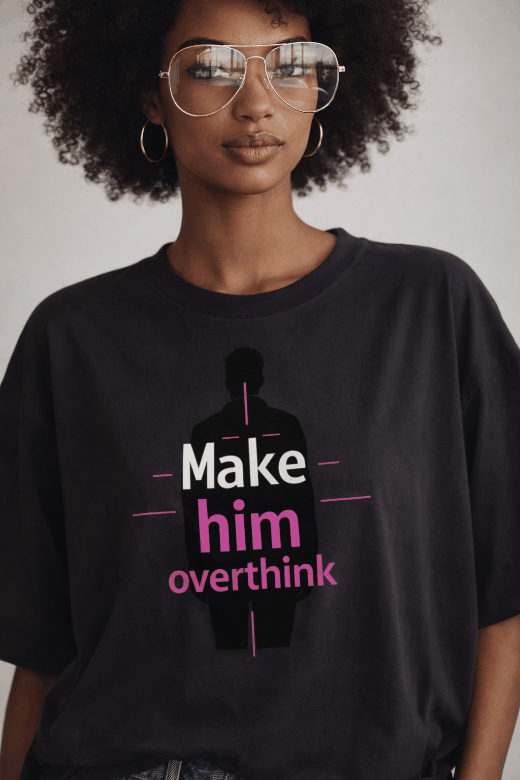 Woman wearing oversized anthracite graphic t-shirt with “Make him overthink” pink typography and silhouette design, bold women’s streetwear look.