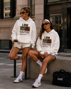 female models wearing oversized white statement hoodies and athletic shorts in urban city environment with noiré coffee accessories streetwear outfit