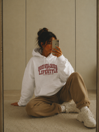 female mirror selfie wearing oversized white hoodie with red varsity typography graphic relaxed streetwear fashion
