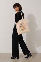 model walking pose carrying beige tote bag with bubble tea graphic relaxed fit outfit neutral tones fashion