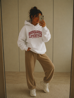 mirror selfie standing pose wearing oversized white graphic hoodie and brown joggers streetwear fashion