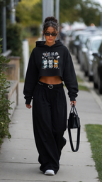model front walking wearing black cropped graphic hoodie with oversized black trousers urban streetwear outfit