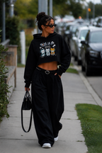 model walking with handbag wearing oversized cropped black hoodie graphic streetwear fashion