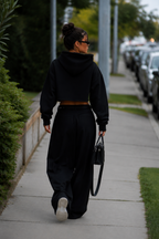 model back walking view wearing black cropped hoodie clean back minimal streetwear fashion
