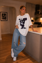 woman posing in modern kitchen wearing oversized white graphic t shirt digital queen illustration urban streetwear outfit