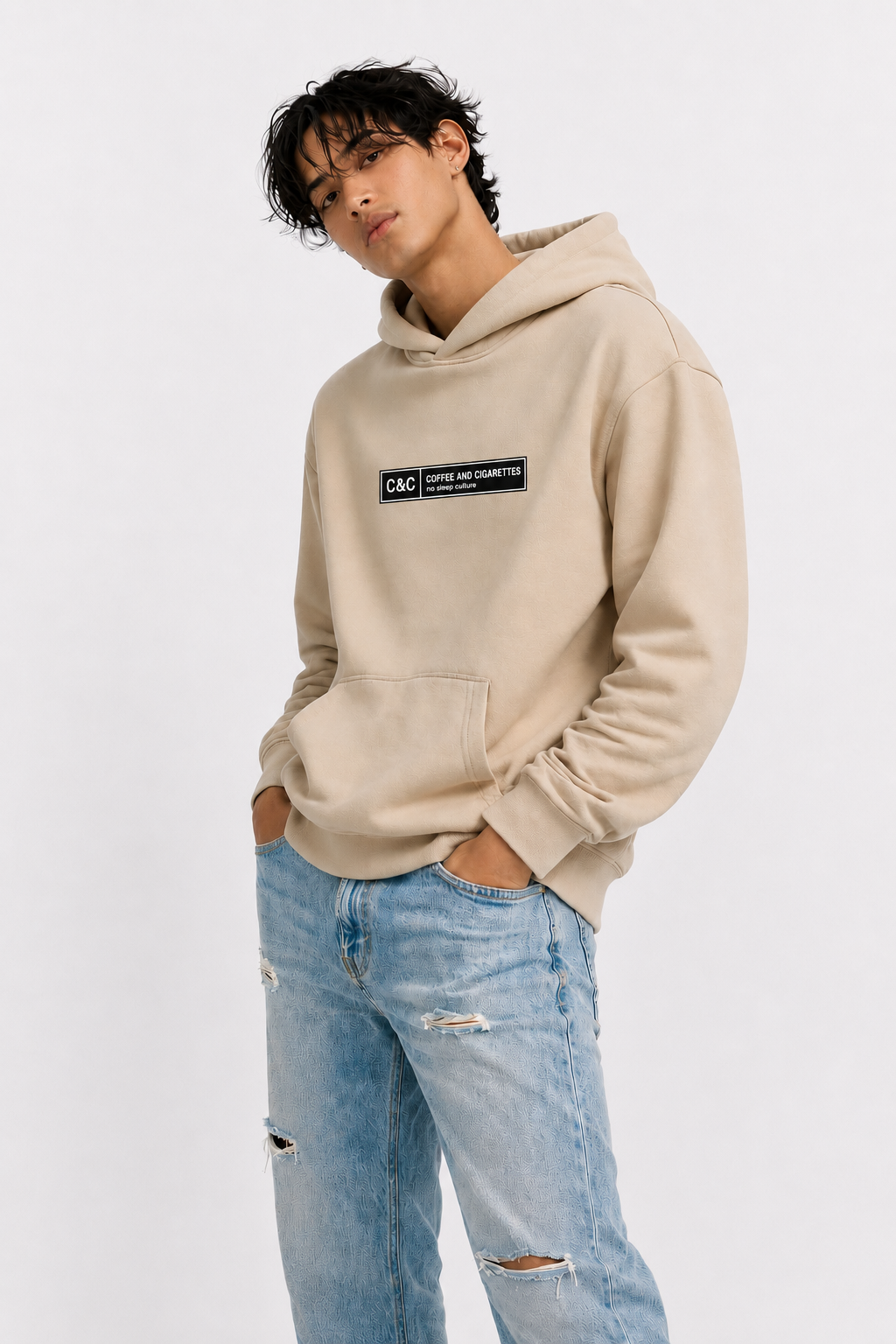 male model side pose wearing oversized beige graphic streetwear hoodie minimal chest logo streetwear fashion
