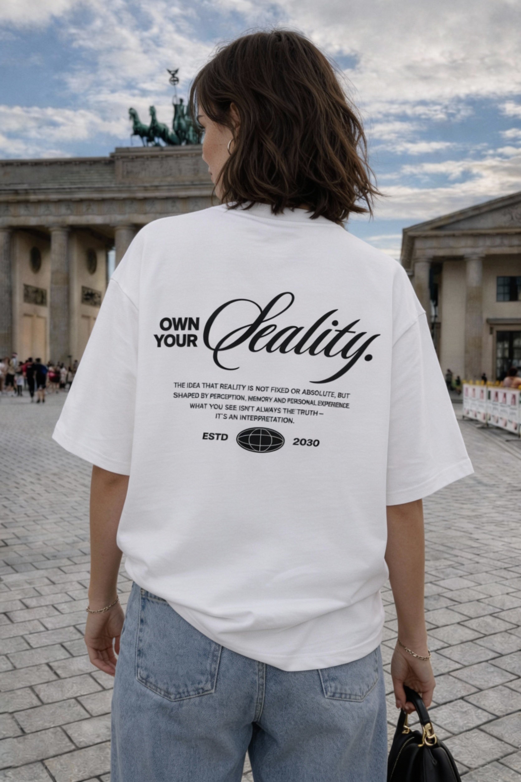 female model close up back view wearing oversized white graphic streetwear t shirt own your reality typography back print streetwear fashion