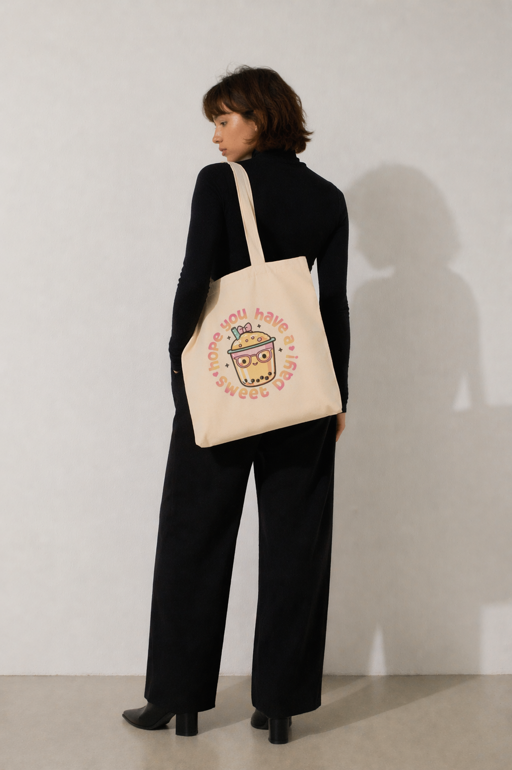 model back view standing wearing beige tote bag bubble tea cute graphic print minimal studio background