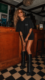 woman posing in vintage bar wearing oversized black graphic t shirt with minimalist Silent Struggles chest print urban streetwear style
