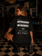 woman seated on floor wearing oversized black graphic t shirt featuring large Introvert back print graphic streetwear fashion