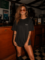 woman facing camera in vintage bar wearing relaxed fit black oversized graphic t shirt with Silent Struggles chest logo urban streetwear outfit