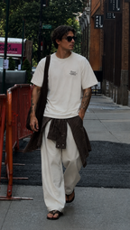 male model walking forward in oversized cream graphic t shirt featuring minimalist chest slogan loose fit casual streetwear fashion