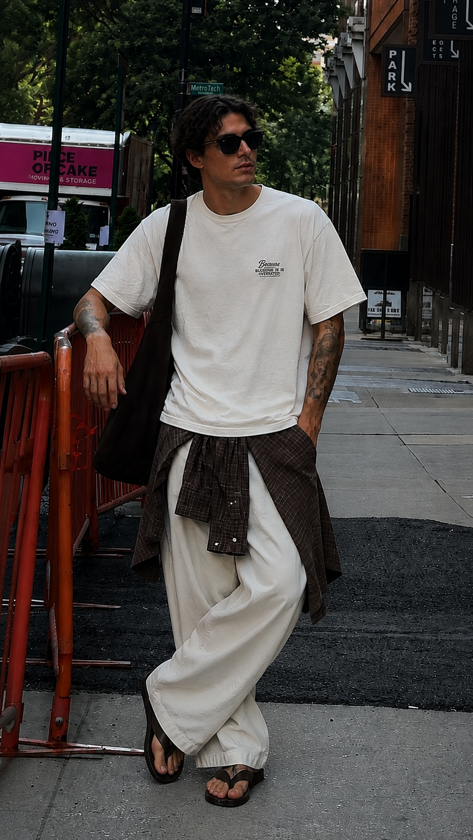 male model standing in city setting wearing oversized cream graphic t shirt with chest typography print relaxed fit streetwear fashion