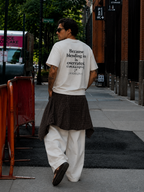 male model posing from rear angle in oversized off white graphic t shirt with because blending in is overrated back design urban streetwear outfit