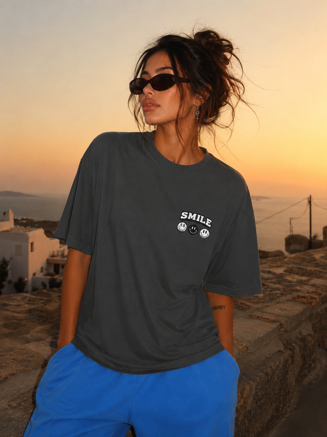 Woman standing wearing oversized charcoal graphic t-shirt front view with relaxed fit, charcoal streetwear fashion outfit