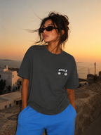 Woman standing with hands in pockets wearing oversized charcoal graphic t-shirt front chest print, modern urban streetwear look