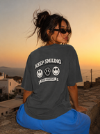 Woman looking sideways wearing oversized charcoal graphic t-shirt front view, relaxed fit graphic streetwear at golden hour