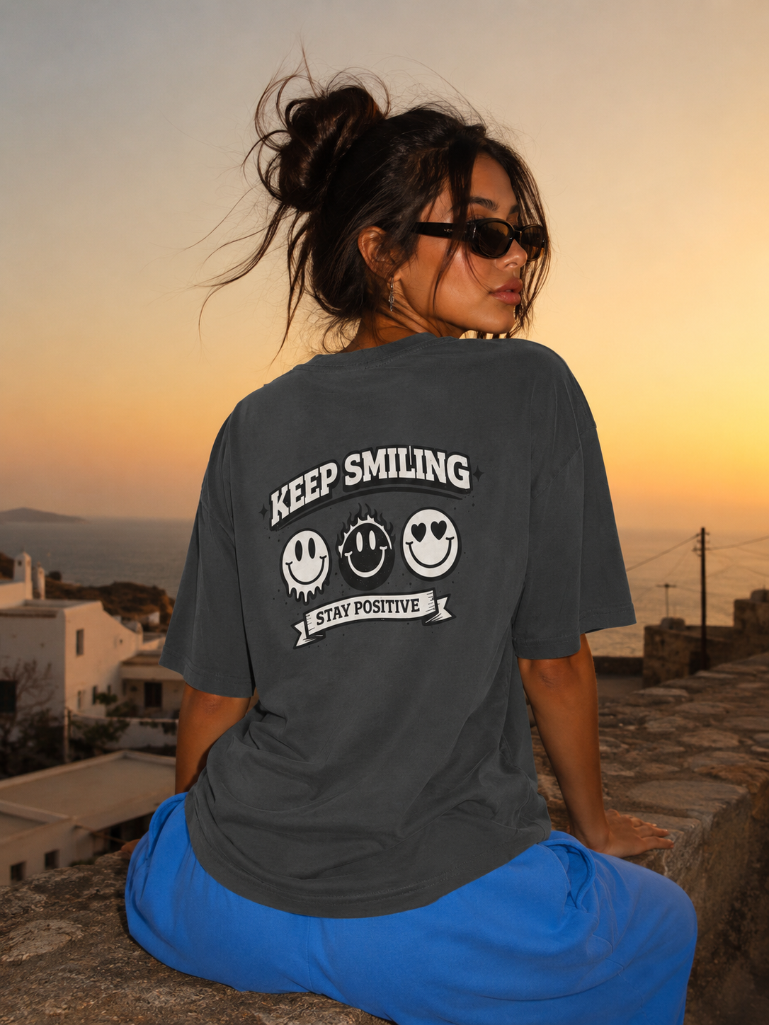Woman looking sideways wearing oversized charcoal graphic t-shirt front view, relaxed fit graphic streetwear at golden hour