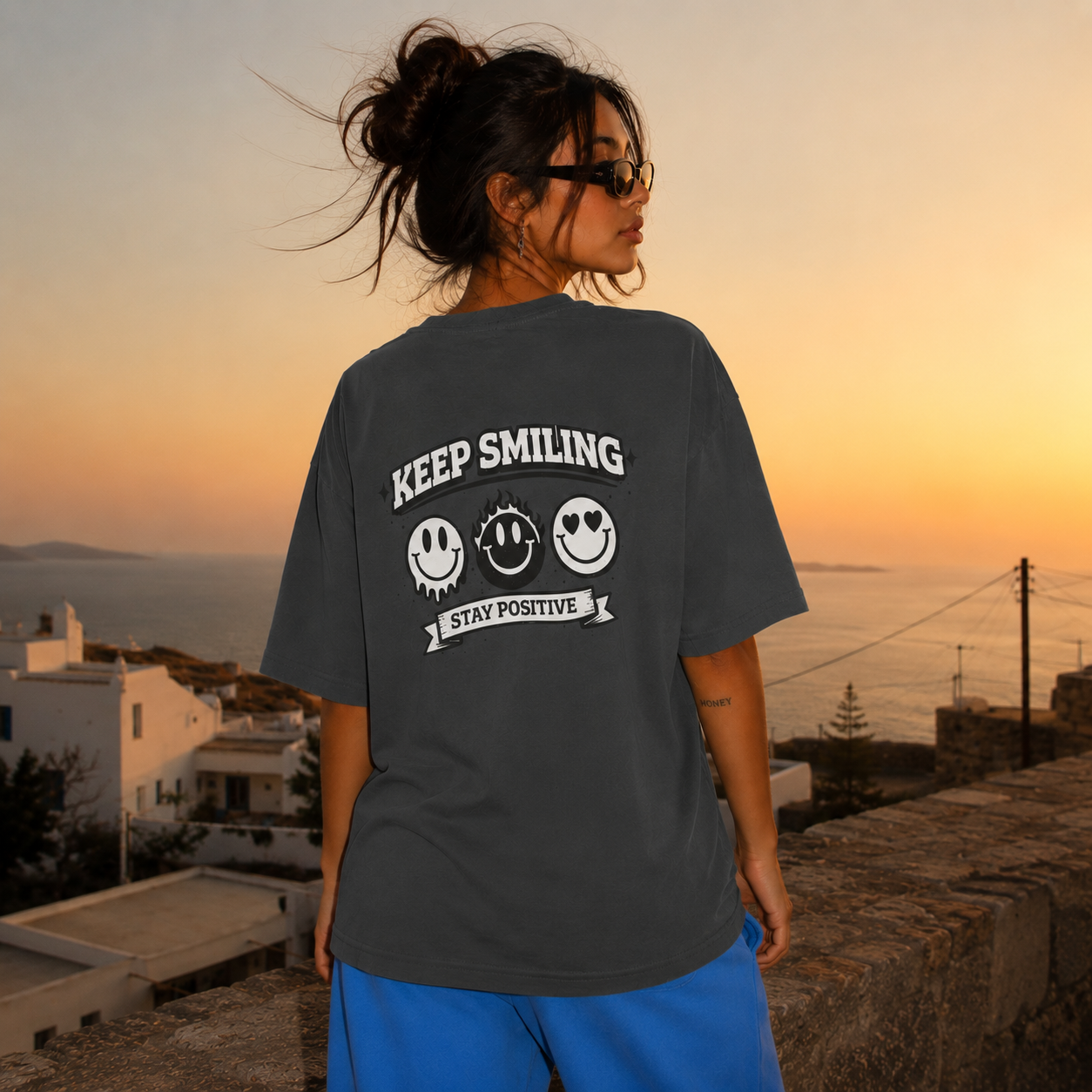 Woman standing back view wearing oversized charcoal graphic t-shirt with Keep Smiling back graphic, relaxed fit streetwear fashion