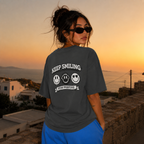 Woman looking over shoulder wearing oversized charcoal graphic t-shirt back view with Keep Smiling design, oversized streetwear style