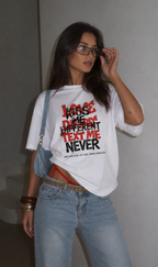 Woman adjusting sunglasses wearing oversized white graphic t-shirt front view with Kiss Me Different Text Me Never design, relaxed urban streetwear outfit